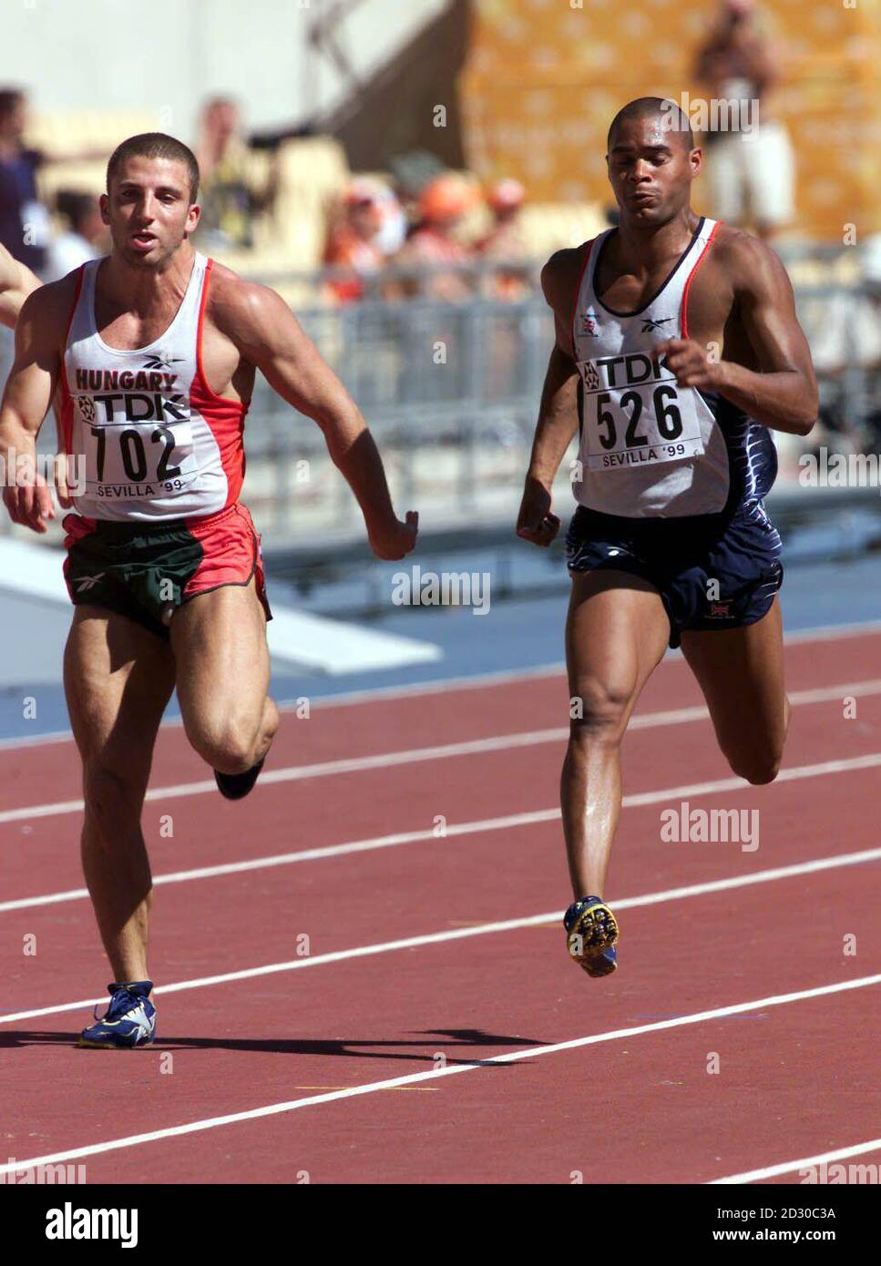 Jason Gardener (derecha) corre en los 100 metros de calefacción, en el Campeonato Mundial de Atletismo de la IAAF 1999 en Sevilla, España. Foto de stock