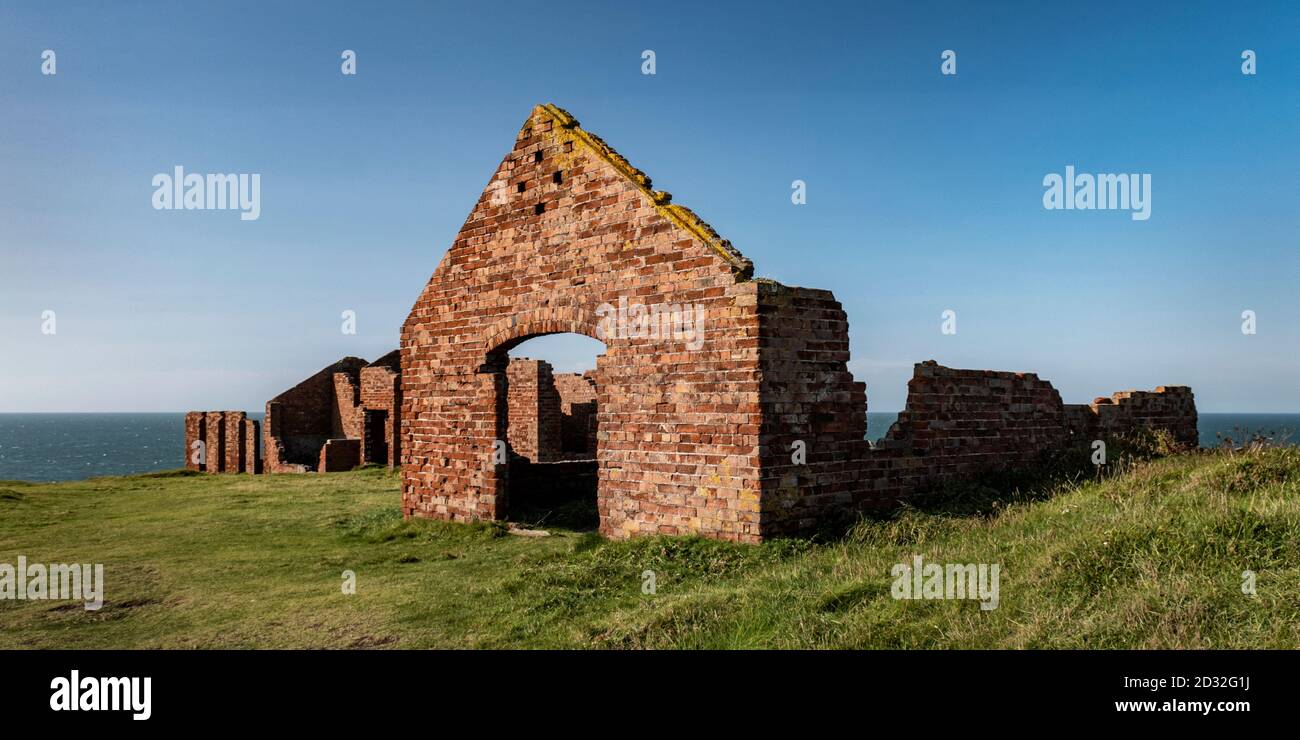 Edificios de ladrillo rojo, ruinas de la actividad de canteras industriales se encuentran en acantilados cerca del puerto de Porthgain, Pembrokeshire Coast National Park, Gales Foto de stock