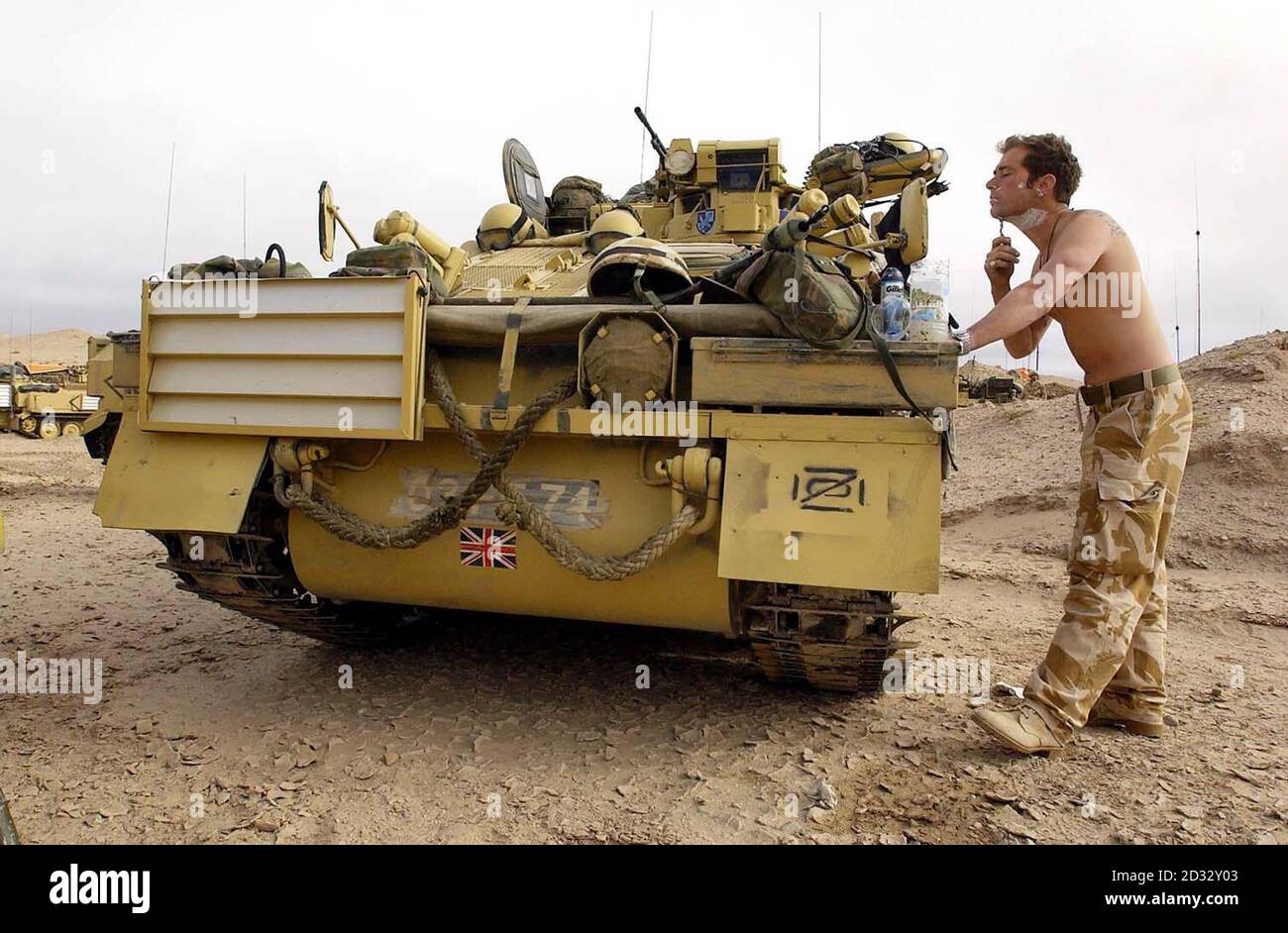 Un soldado tiene un afeitado usando los espejos de alas de su tanque espartano, mientras las tropas británicas de la Caballería de la Casa esperan en las alas mientras las fuerzas estadounidenses son enviadas más lejos a Irak. Foto de stock