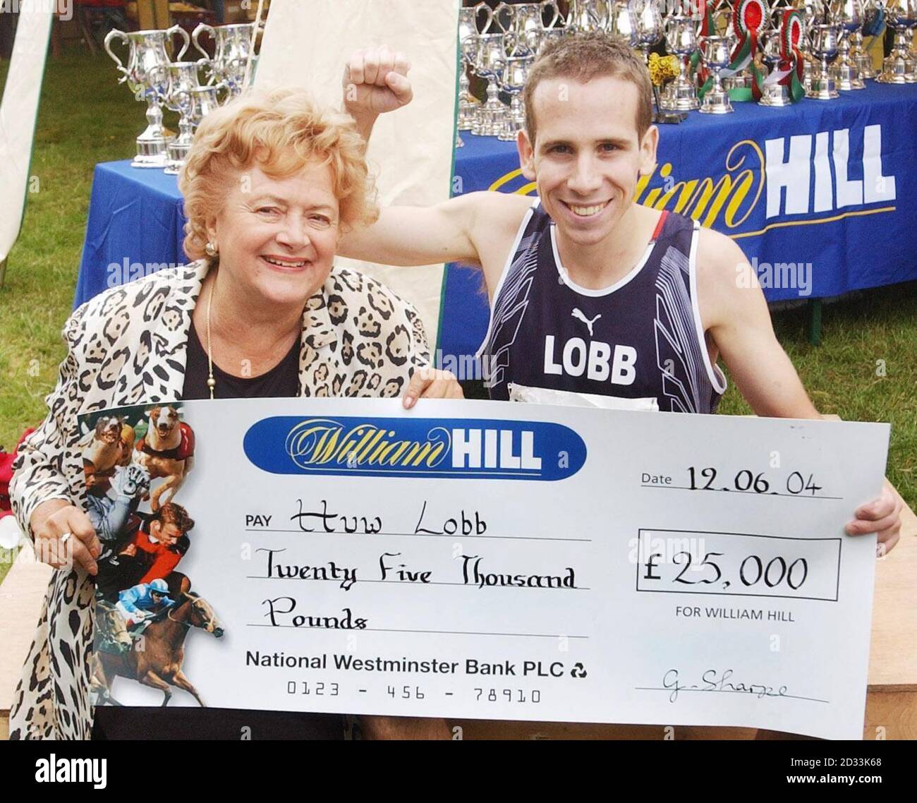 Huw Lobb recoge su cheque para 25,000 de Cynthia Payne después de su victoria en el williamhill.co.uk Man v Horse Marathon en el Medio Gales. Foto de stock