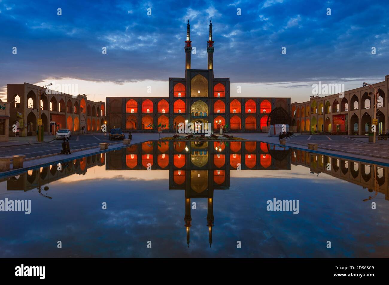 La fachada del complejo Amir Chaqmaq se ilumina al amanecer y se refleja en un estanque, Yzad, provincia de Yazd, Irán Foto de stock