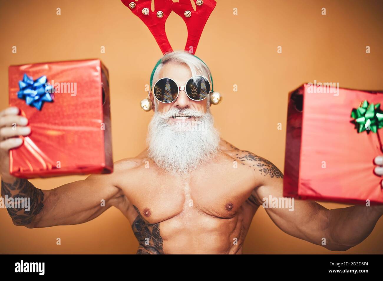 Feliz ajuste de la tercera edad con regalos de Navidad - Hipster hombre  mayor divertirse dando caja de regalo durante las vacaciones de navidad  Fotografía de stock - Alamy