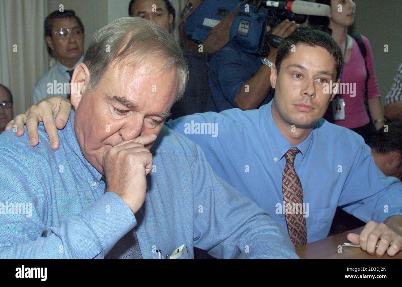 El periodista británico Rodney Tasker, de 56 años (L), es consolado por su  colega estadounidense Shawn Crispin, de 33 años, después de reunirse con la  policía de inmigración en Bangkok el 27