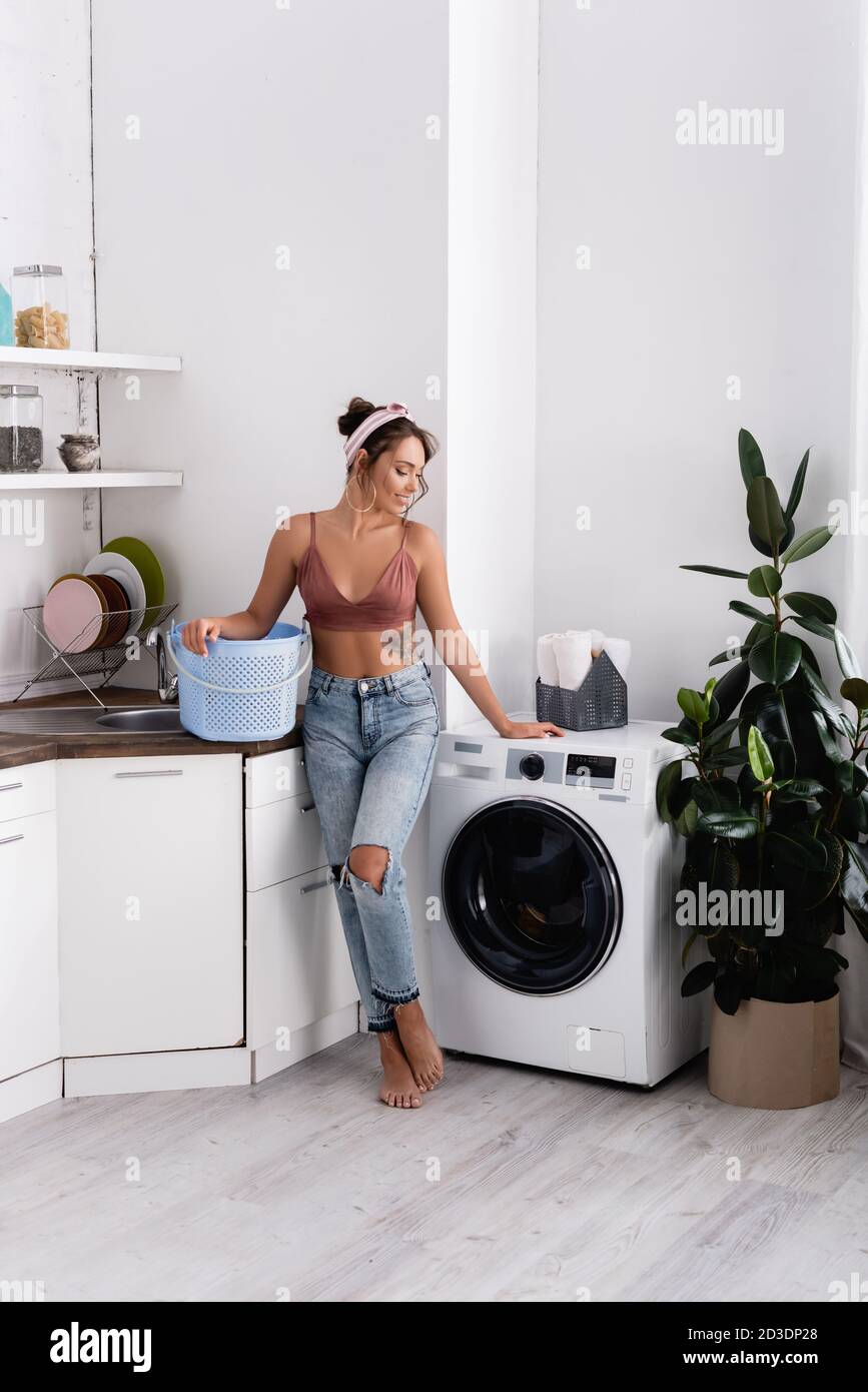 Ama de casa descalzo sosteniendo una cesta de ropa cerca de la lavadora en  la cocina Fotografía de stock - Alamy