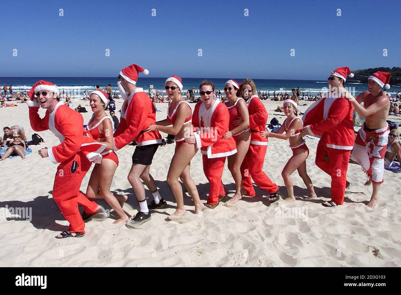 Los turistas ingleses vestidos como hombres y mujeres Santas forman una  línea de conga en la playa Bondi de Sydney el día de Navidad el 25 de  diciembre de 2000. Miles de