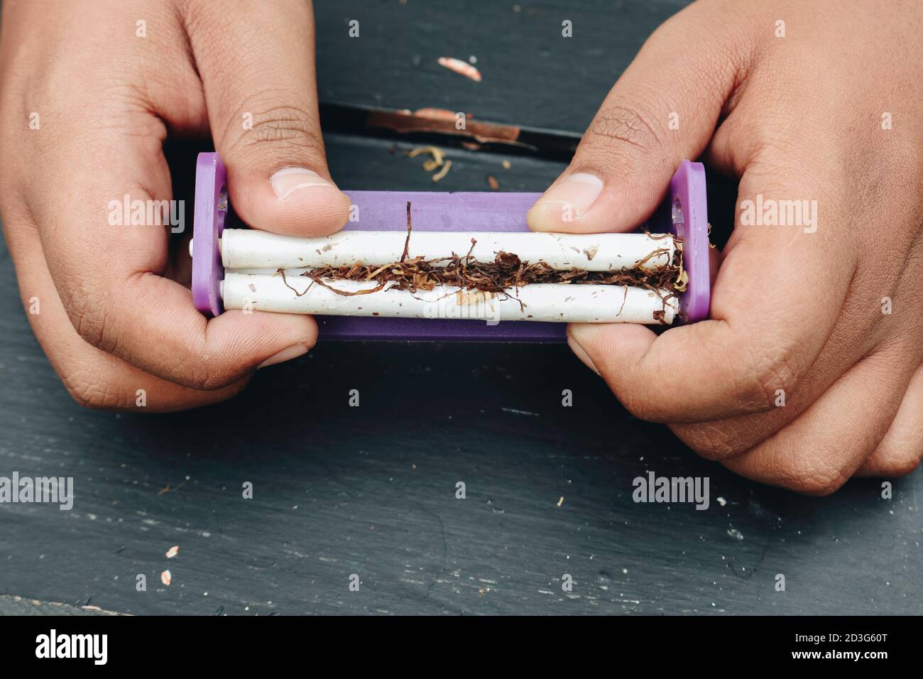 Man Hand hace un cigarrillo con herramientas tradicionales rodantes, Hands closeup. Foto de stock