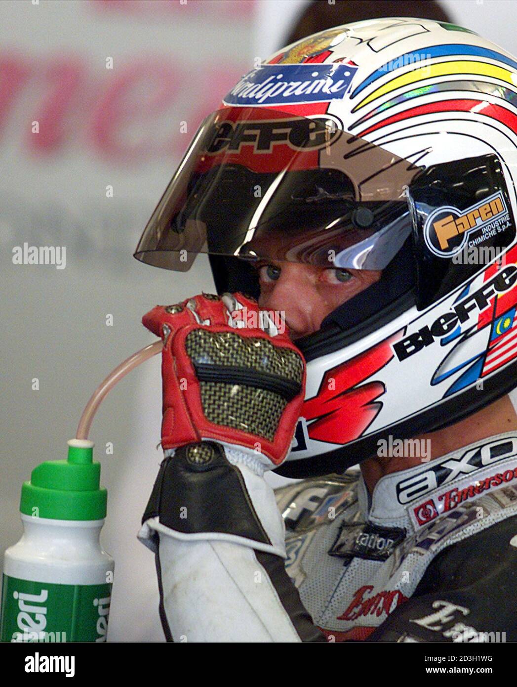 El piloto italiano de 500cc Loris Capirossi bebe a través de su casco con  una paja en su garaje en la pista de Estoril 1 de septiembre de 2000. Loris  Capirossi se