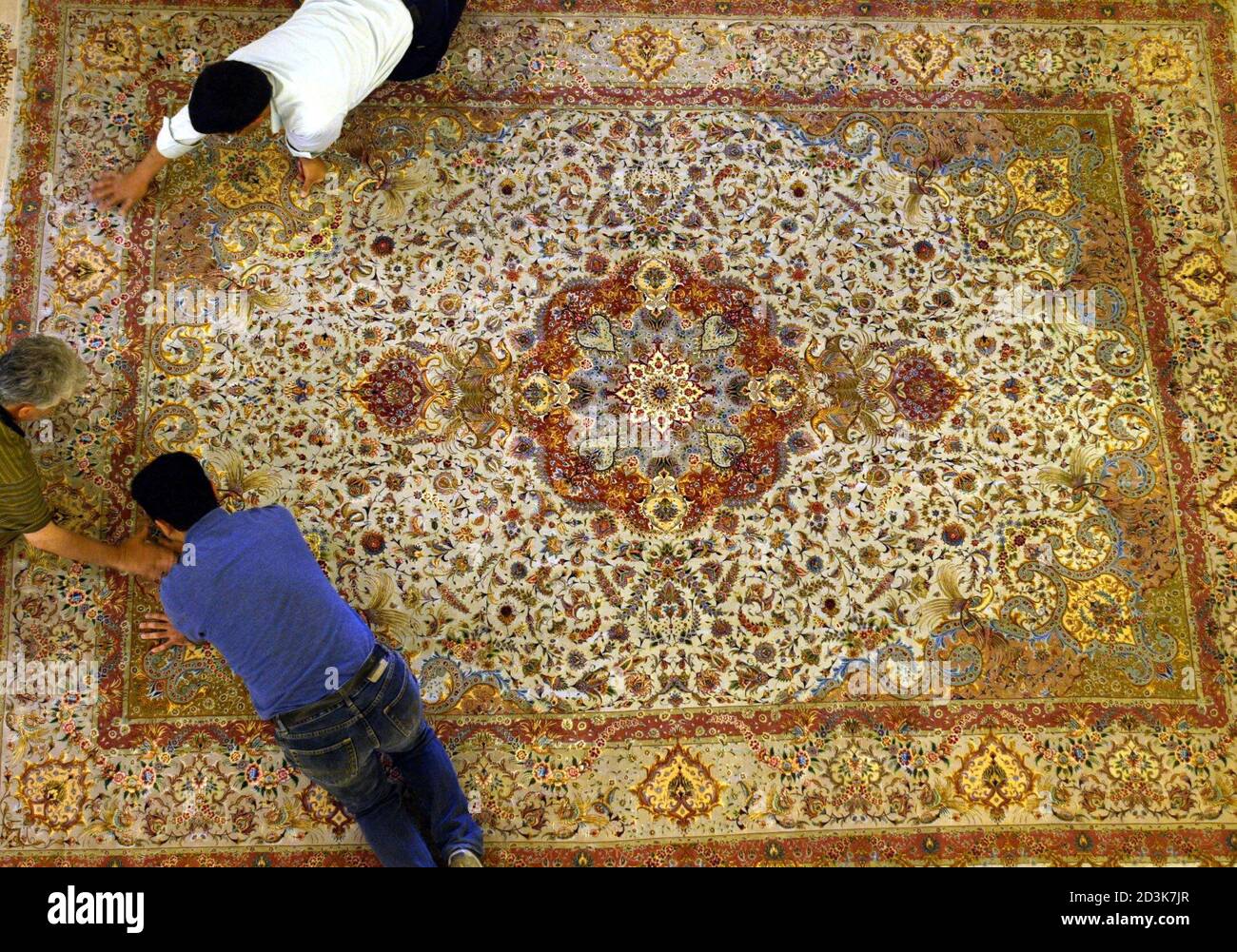 Hombres iraníes ajustan una alfombra de colores Tabriz hecha a mano en una  exposición de alfombras hechas a mano iraní en Amman 21 de mayo de 2003. La  alfombra de quinientos colores,