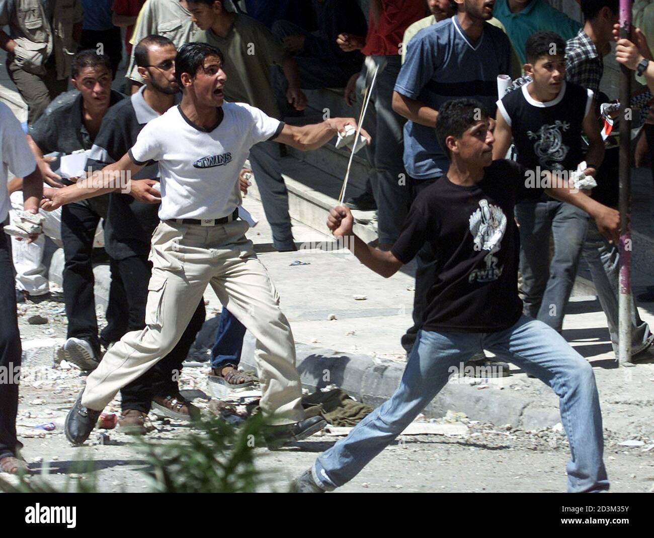 Jóvenes palestinos lanzaron piedras contra soldados israelíes durante enfrentamientos en la ciudad de Hebrón, en la Ribera Occidental, el 13 de agosto de 2001. Los palestinos de la Franja de Gaza y la Ribera Occidental cerraron tiendas y oficinas el lunes en protesta contra la toma por parte de Israel de la emblemática sede palestina en Jerusalén. NH Foto de stock