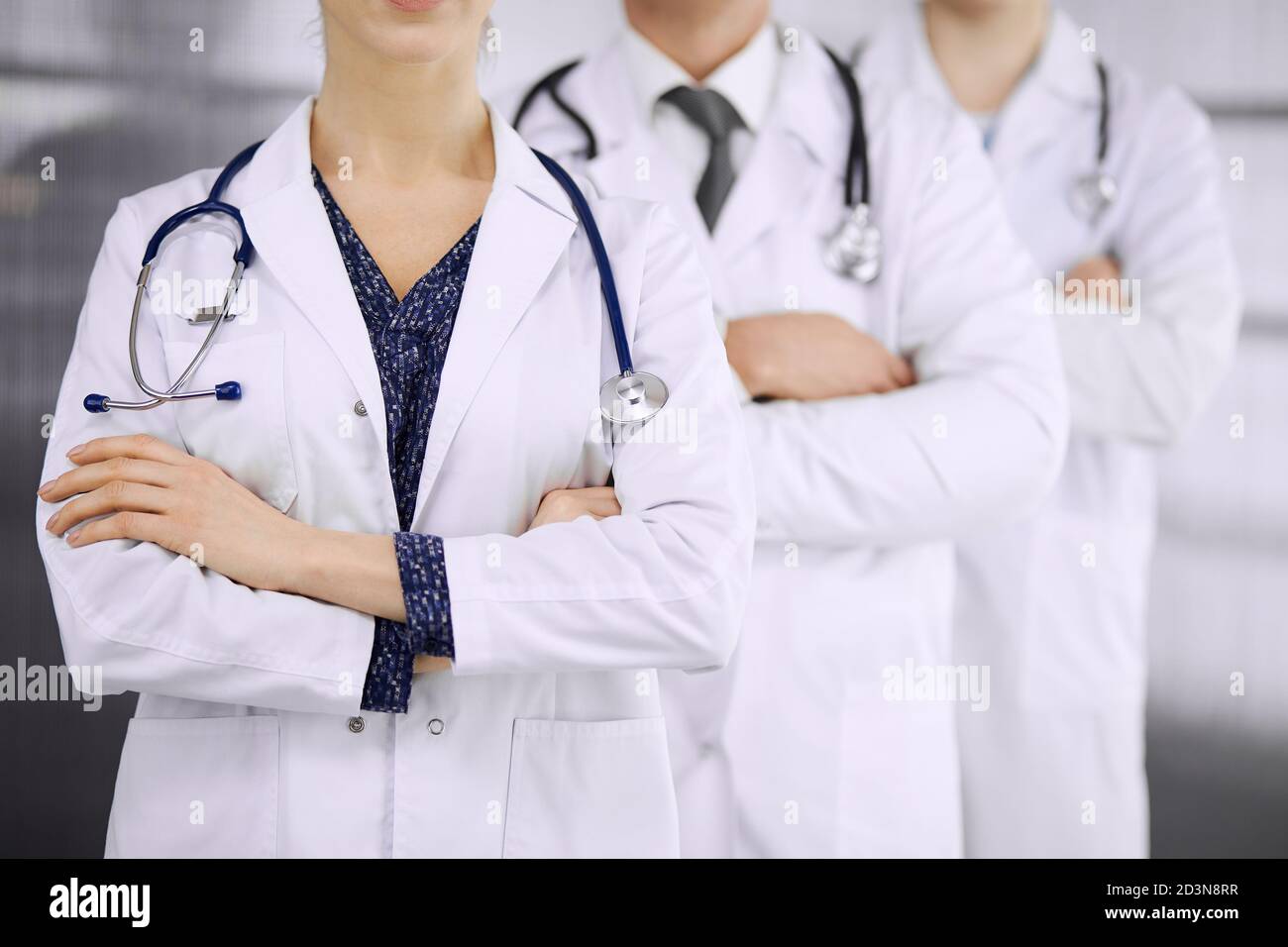 Médicos de pie como un equipo con los brazos cruzados en la clínica. Ayuda médica, seguro y concepto de medicina Foto de stock