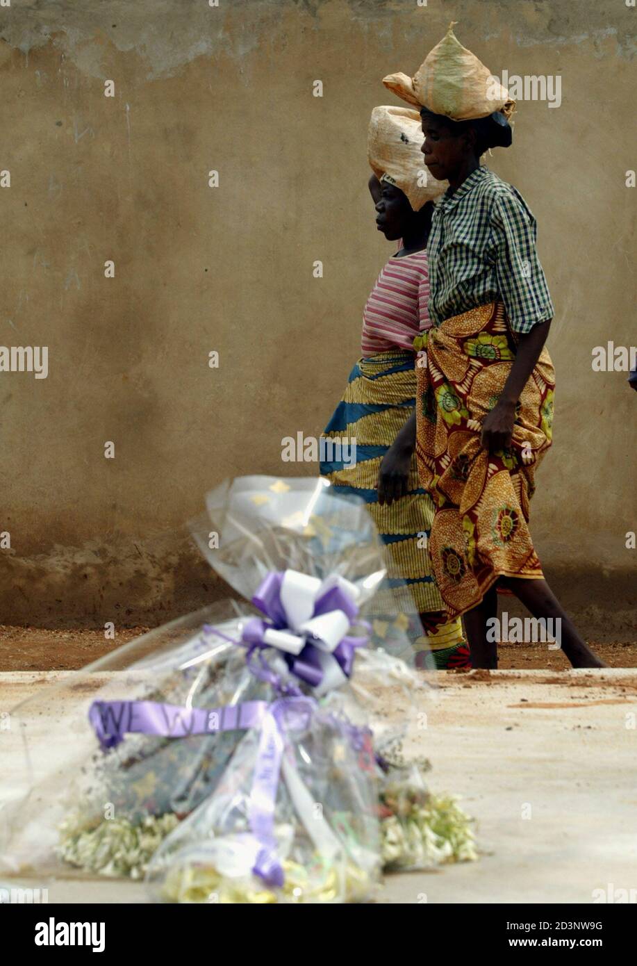 Rwandan workers pass behind of cement covered mass grave at the Gisozi genocide memorial in Kigali April 2, 2004. Rwanda expressed regrets and resignation that Western leaders were conspicuously absent from a list of foreign dignitaries scheduled to attend memorial ceremonies in Kigali next week marking the 10th anniversary of Rwanda's 1994 genocide. REUTERS/Radu Sigheti RS/ Foto de stock
