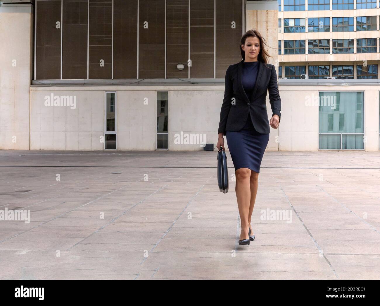 Hermosa mujer de negocios saliendo de la oficina con caminar con confianza  vestido de elegante traje y maletín Fotografía de stock - Alamy