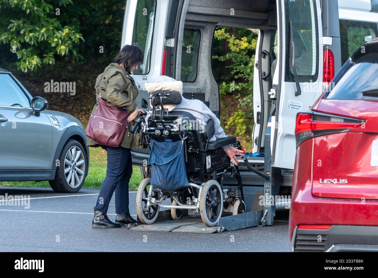 Persona discapacitada y cuidador usando el ascensor en una silla de ruedas minibús accesible Foto de stock