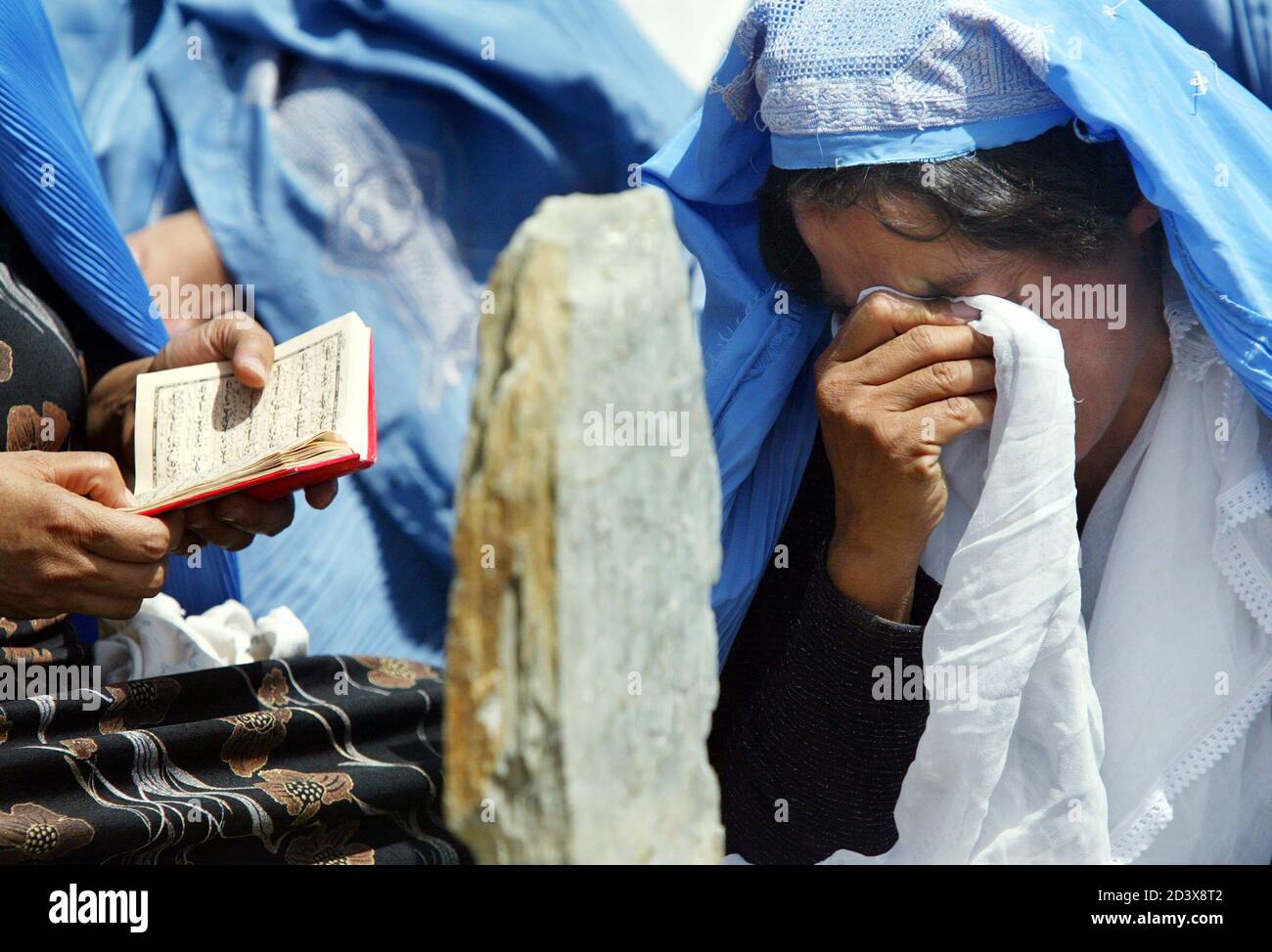 Una mujer afgana llora frente a la lápida de un miembro de la familia que  se ha ido, ya que se leen versos sagrados en un cementerio de Kabul, el 27  de