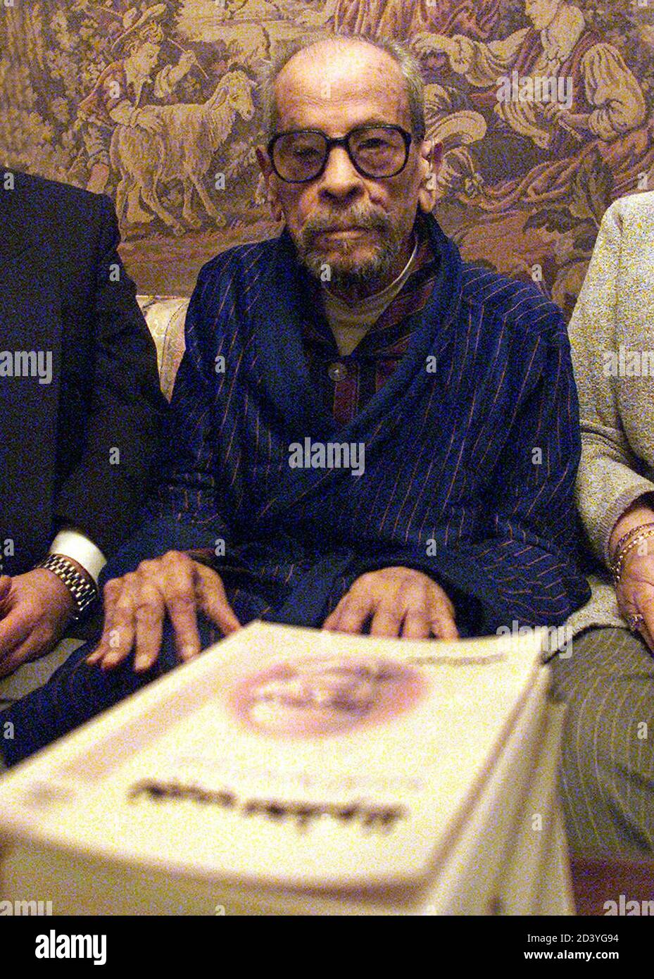 Naguib Mahfouz, premio Nobel de Literatura de Egipto, se presenta delante de la última biografía que le presentaron sus amigos un día antes de su 90 cumpleaños en su casa en el Cairo el 10 de diciembre de 2001. Mahfouz se convirtió en el primer escritor en árabe en ganar el premio Nobel en 1988. En 1994 fue apuñalado por un militante musulmán en un intento fallido de asesinato, después de que los militantes lo declararan infiel por su imagen de Dios en la novela "los hijos de Gebelawi". REUTERS/Aladin Abdel Naby AN/WS Foto de stock