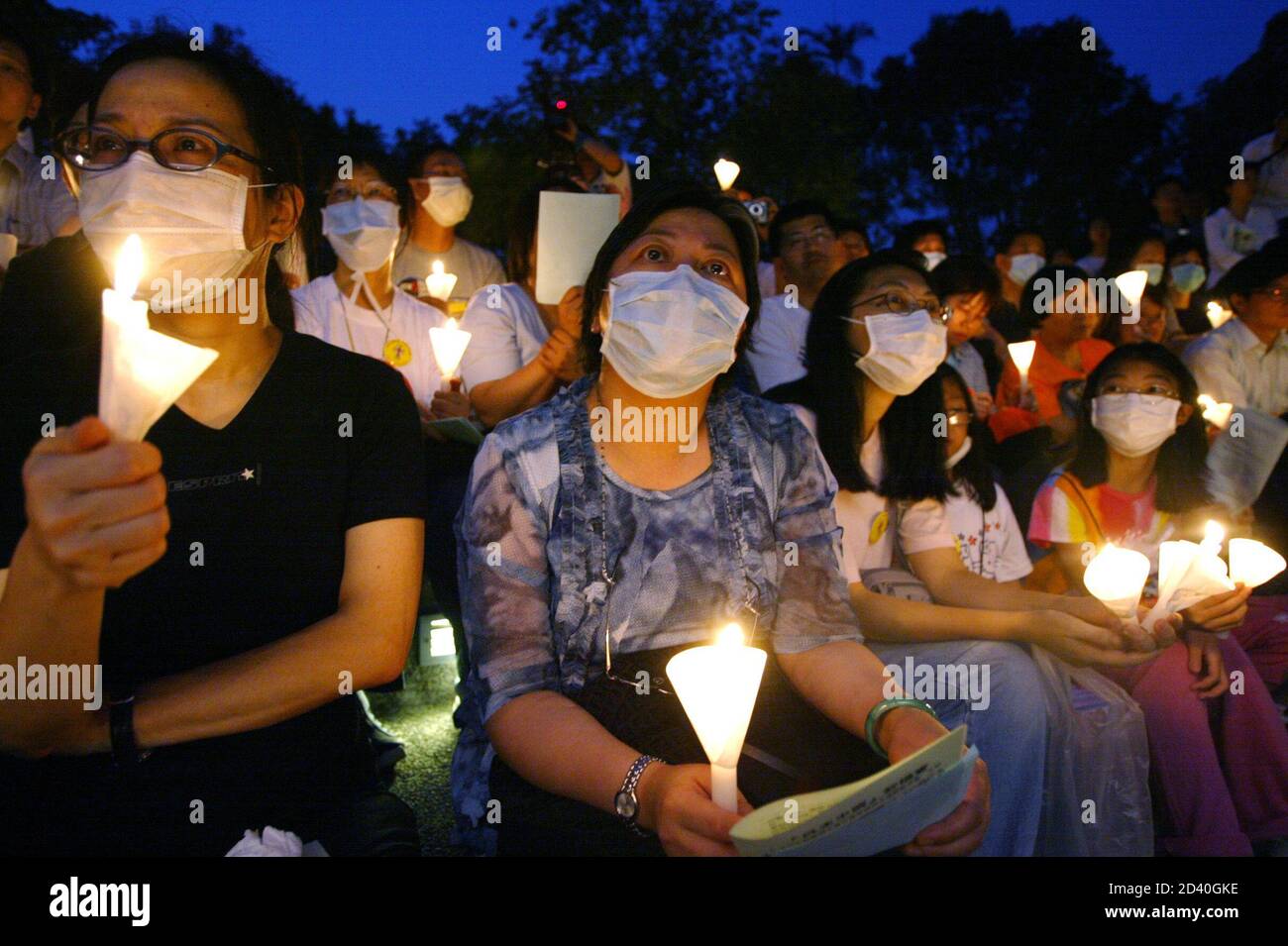 Los cristianos que usan máscara contra el mortal virus del SARS, asisten a una sesión de oración durante una vigilia a la luz de las velas en Hong Kong el 4 de junio de 2003 para recordar la masacre de Tiananmen en China hace 14 años. La multitud se inclinó tres veces para honrar a los cientos, tal vez miles, de víctimas del 3 y 4 de junio cuando las tropas y tanques chinos aplastaron las manifestaciones prodemocráticas lideradas por los estudiantes en la plaza Tiananmen de Beijing. REUTERS/Kin Cheung KC/DL Foto de stock