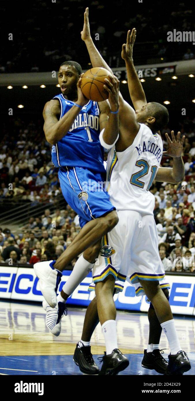 El guarda de Orlando Magic Tracy McGrady (L) mira para pasar mientras él  choca con el centro de New Orleans Hornets Jamaal Magloire durante el  abrelatas de la casa para la magia