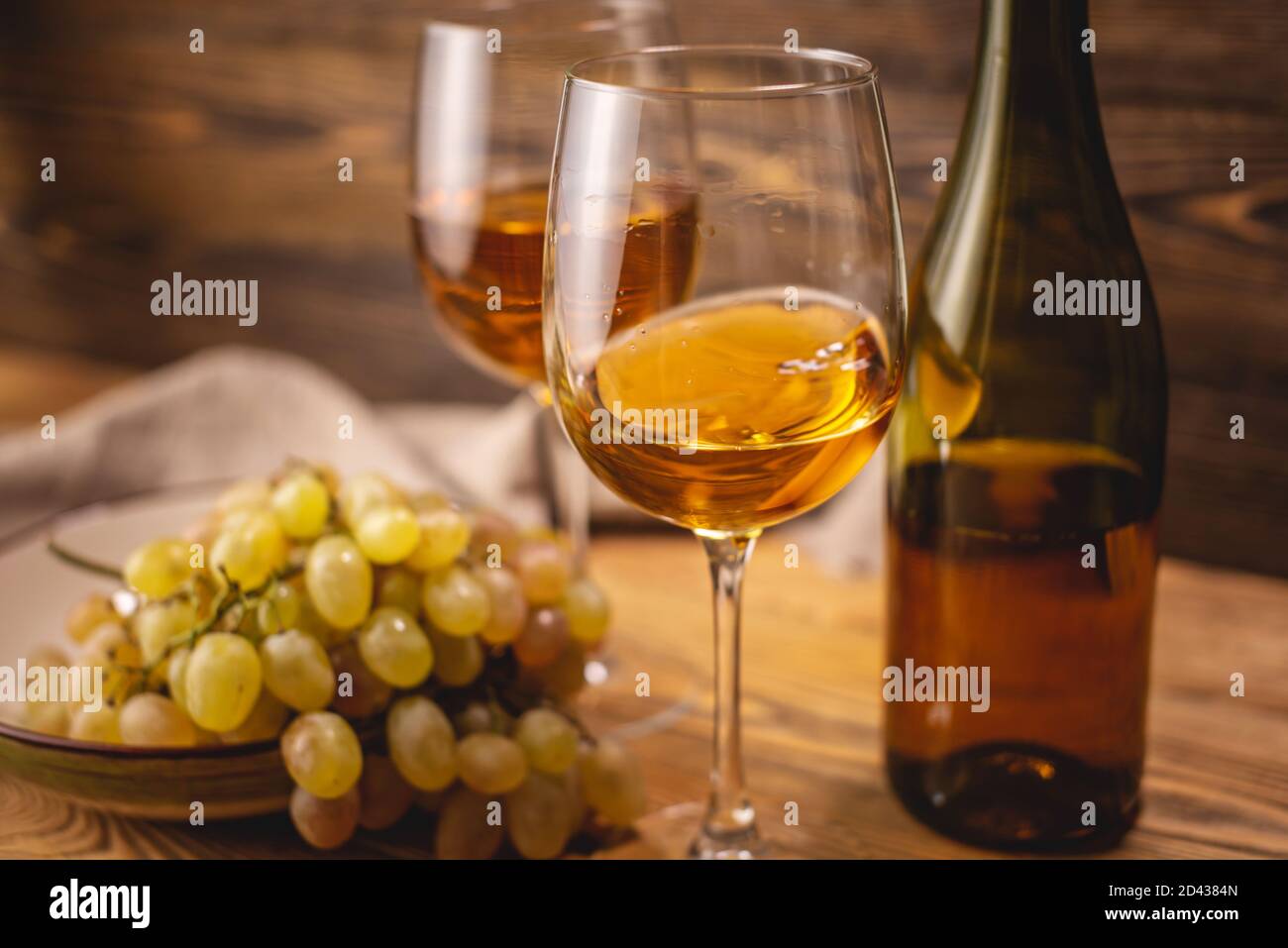 Una botella de vino blanco seco con un vaso y un montón de uvas sobre una mesa de madera. Concepto de viticultura y vinificación Foto de stock