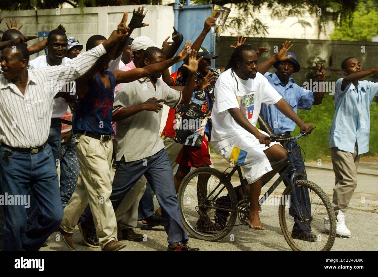 Haitian-American rap star and Grammy Award-winner Wyclef Jean, (on bike)  formerly of The Fugees, rides a bicycle in the yard of the World Food  Program (WFP) warehouse in Port-au-Prince, Haiti, on October