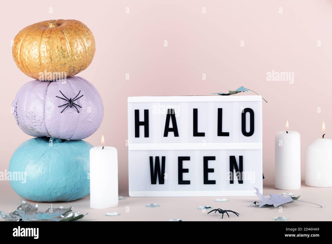 caja de luz con texto de halloween y calabazas azules púrpura y oro con velas sobre fondo rosa. Saludo de vacaciones, concepto de invitación. Foto de stock