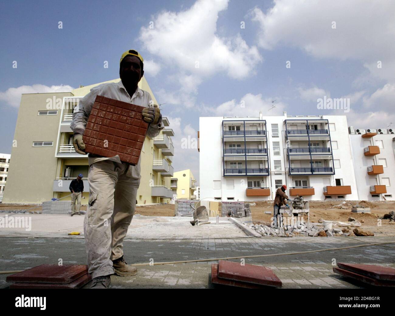 - PHOTO TAKEN 10OCT03 - A worker lifts a tile during construction works at the Olympic Village in Athens October 10, 2003. The village will host some 10,000 athetes and team members during the Athens 2004 Olympic Games. Foto de stock