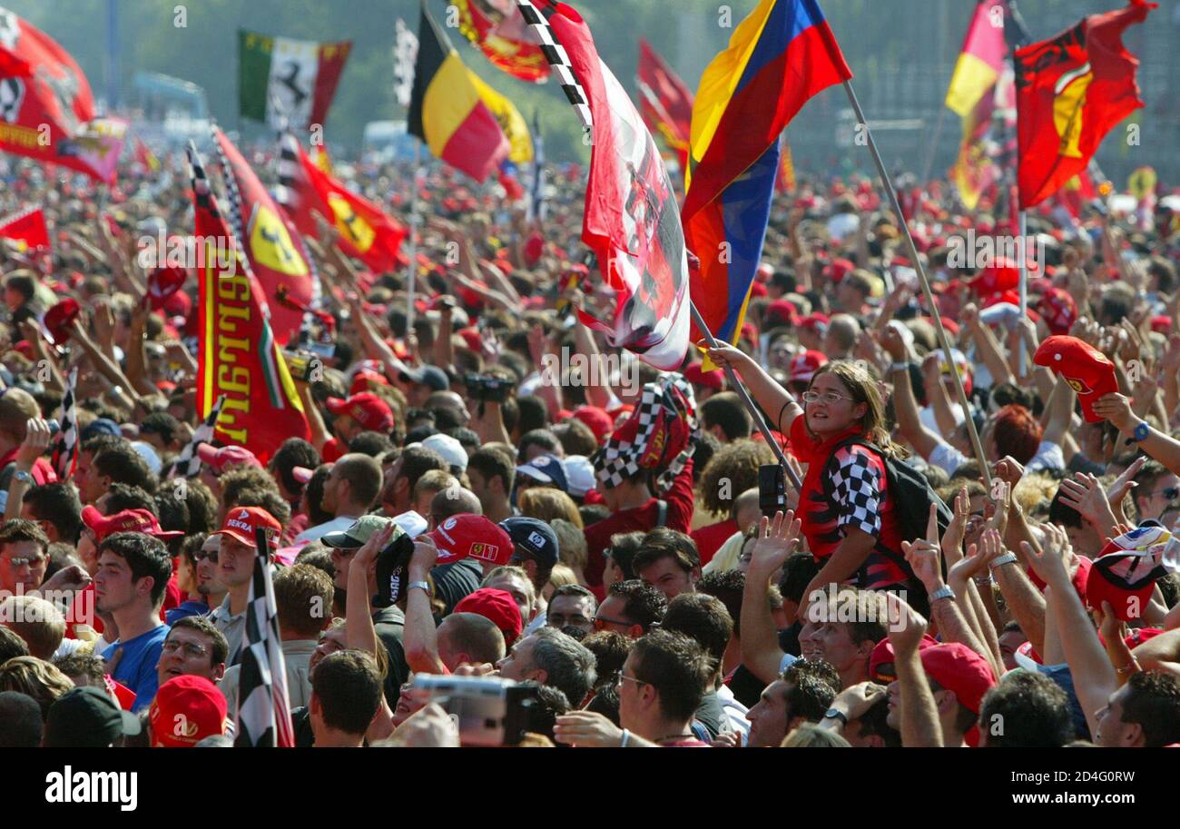 Los fans de Ferrari celebran la victoria del piloto brasileño de Ferrari Rubens Barrichello, el segundo compañero de equipo alemán campeón del mundo Michael Schumacher y el tercer piloto irlandés de Jaguar Eddie Irvine en el podio al final del GP italiano en Monza pista 15 de septiembre de 2002. El brasileño Rubens Barrichello llevó a Michael Schumacher a una victoria de un dos antes de un mar rojo de fans de Ferrari en su hogar Gran Premio de Italia el domingo. Foto de stock