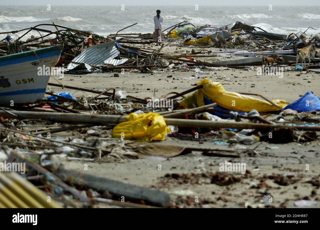 Un hombre indio camina entre los escombros que quedaron tras un tsunami golpeó la playa de Velankani en las afueras de Nagapattinam, a 350 km (219 millas) al sur de la ciudad India de Madras, el 28 de diciembre de 2004. Las Naciones del Océano Índico, desde Indonesia hasta Sri Lanka, lucharon el martes para encontrar y enterrar a sus muertos y ayudar a los sobrevivientes de las olas de marea a medida que crecían los temores el número final superaría con mucho a las 27,700 personas reportadas muertas. REUTERS/Unidad Paranjpe PP/FA Foto de stock