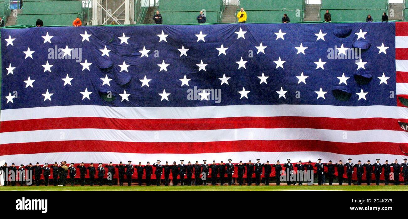 Los miembros de todos los servicios armados de los Estados Unidos se encuentran bajo una gigantesca bandera de los Estados Unidos que se encuentra en el famoso muro de campo izquierdo de 'Green Monster' de Fenway Park mientras se toca el himno nacional de los Estados Unidos antes de que los Red Sox programaran el juego de apertura en casa el 11 de abril de 2003 en Boston. El partido de béisbol entre los Medias Rojas de Boston y los Orioles de Baltimore fue llamado y retrasado hasta otro día debido a la fuerte lluvia. REUTERS/Jim Bourg REUTERS JRB Foto de stock