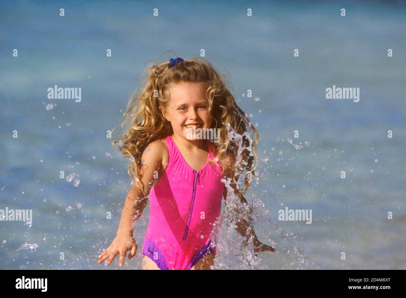 chica feliz chapoteando en el agua en la playa Foto de stock