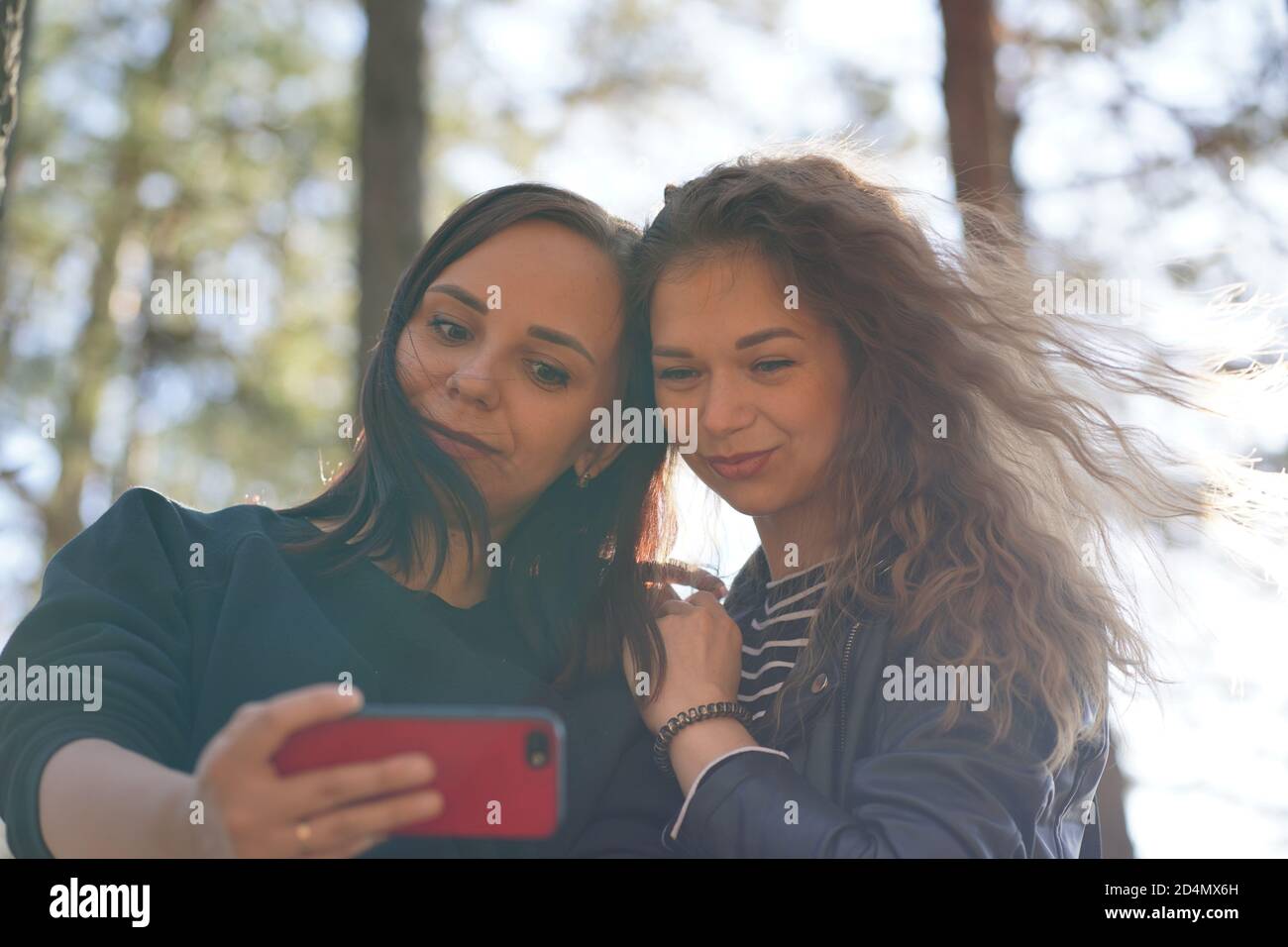 Primer plano de mujeres jóvenes tomando selfie en el smartphone en madera. Bonitas mujeres fotografiando en el teléfono móvil. Foto de stock