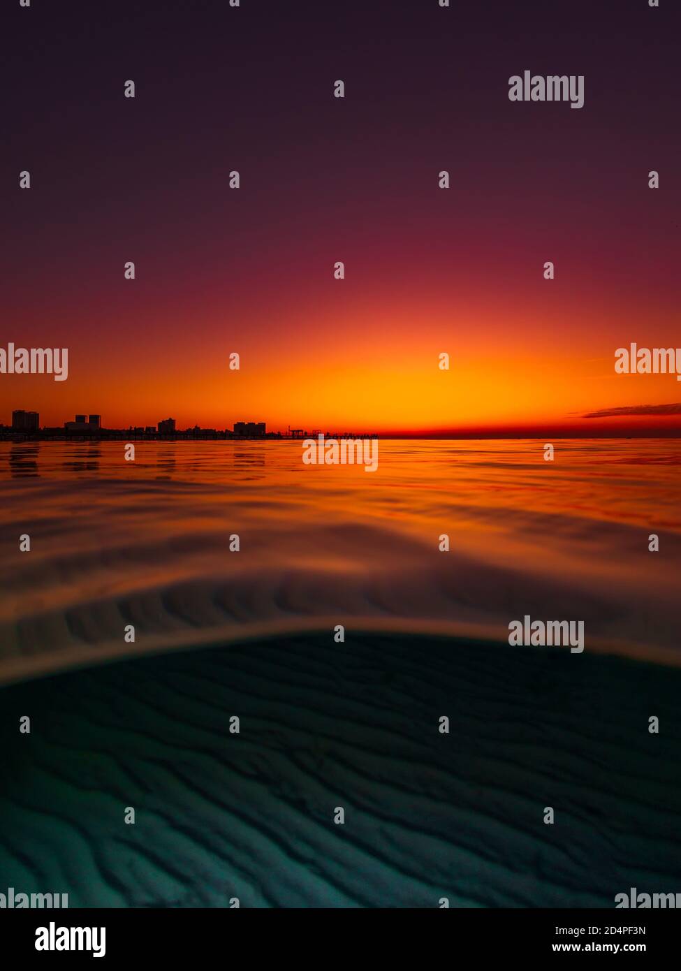 Vista dividida con puesta de sol brillante y fondo de mar de arena bajo el agua. Foto de stock