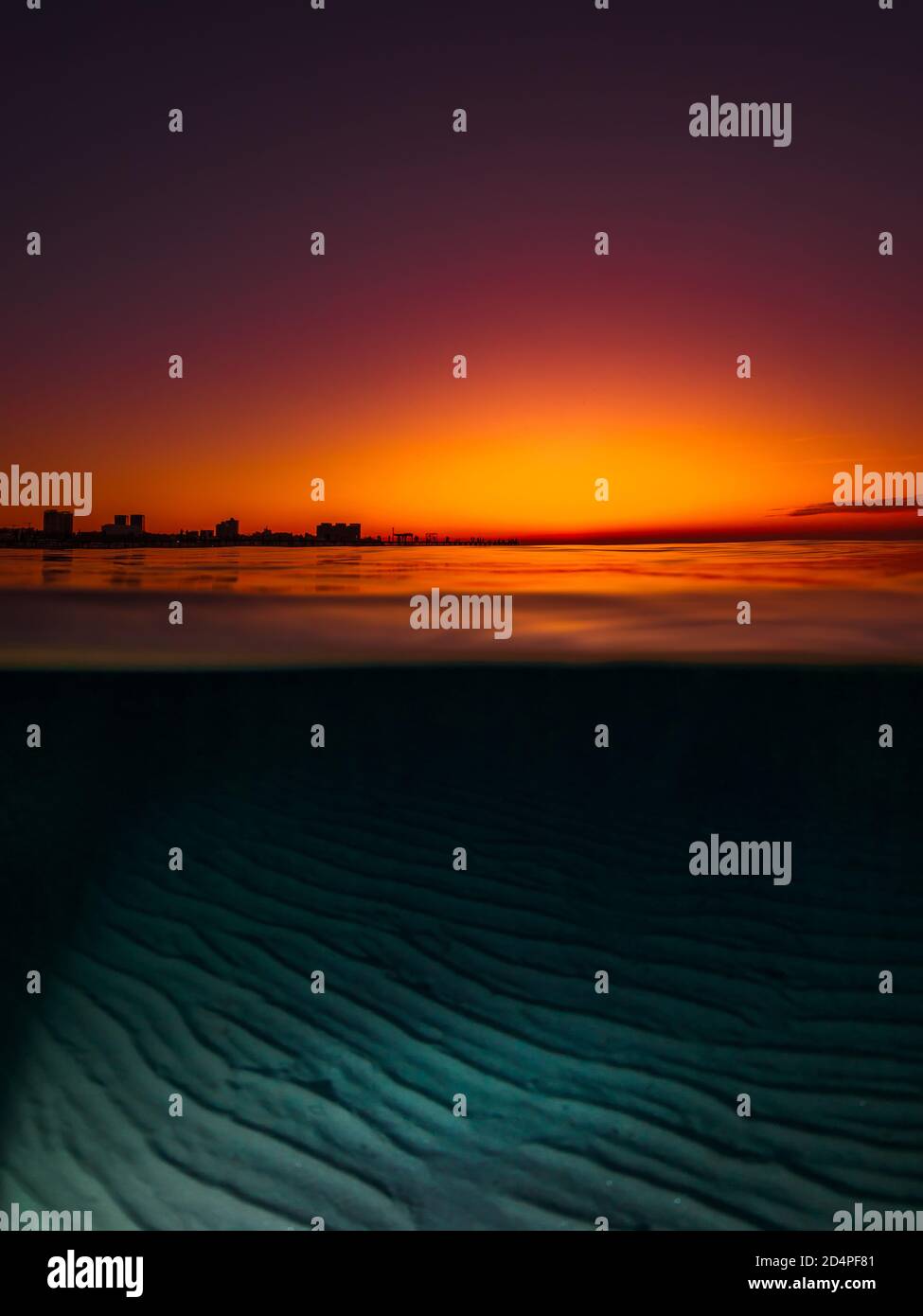 Vista dividida con puesta de sol brillante y fondo de mar de arena bajo el agua. Foto de stock