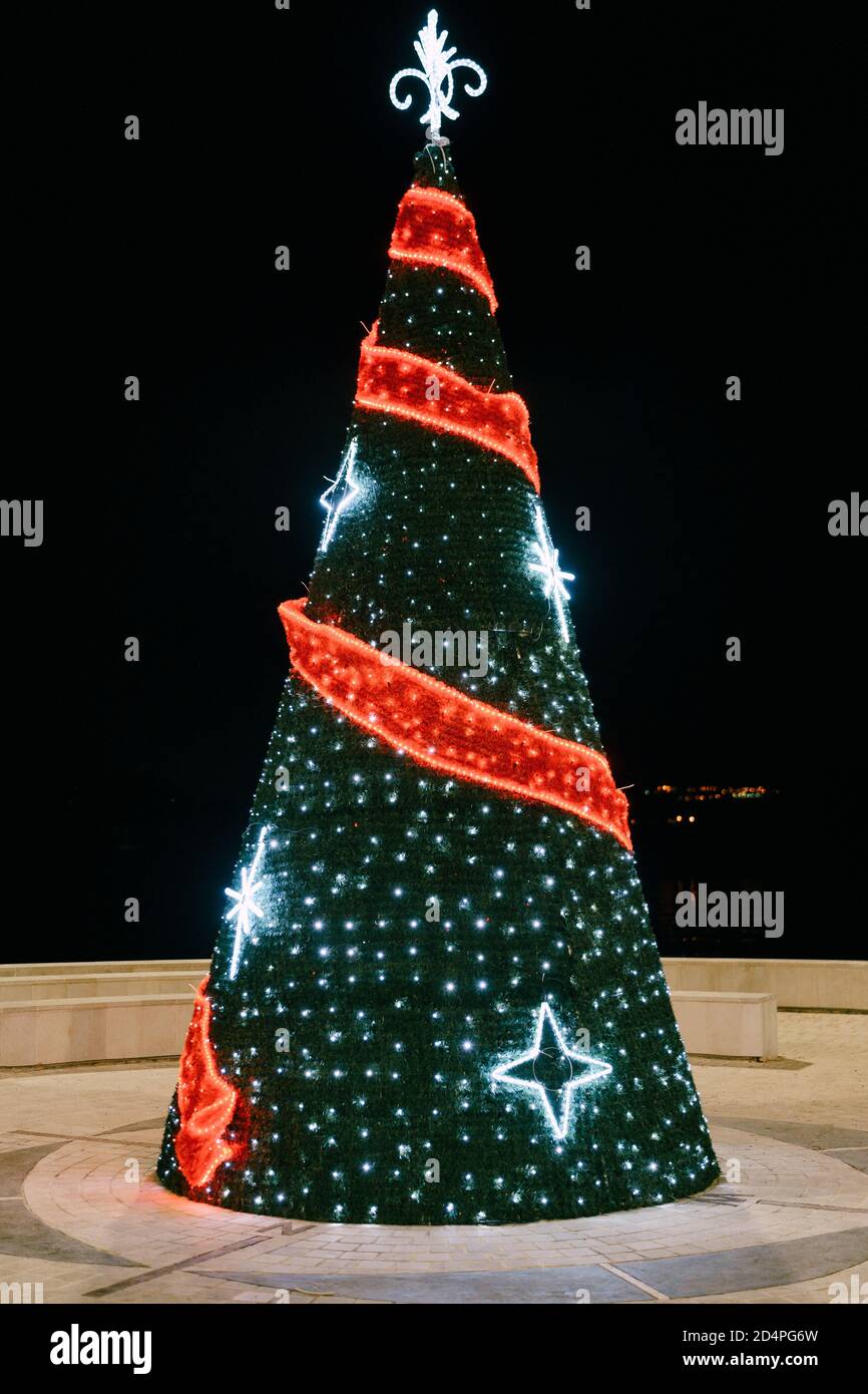 Un árbol de Navidad en forma de cono decorado con guirnaldas en la plaza  del pueblo Fotografía de stock - Alamy