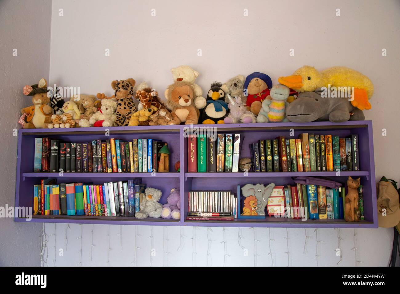Estante con libros y juguetes suaves y esponjosos en un niño dormitorio Foto de stock