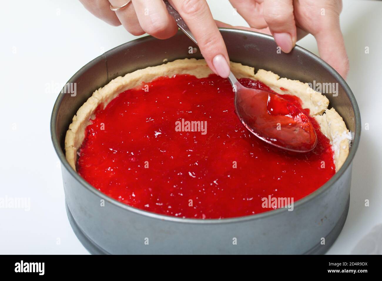 Una mujer cubre copos de coco en un bizcocho con ganache de chocolate con  jalea de frambuesa. Levington pastel, etapas de preparación Fotografía de  stock - Alamy