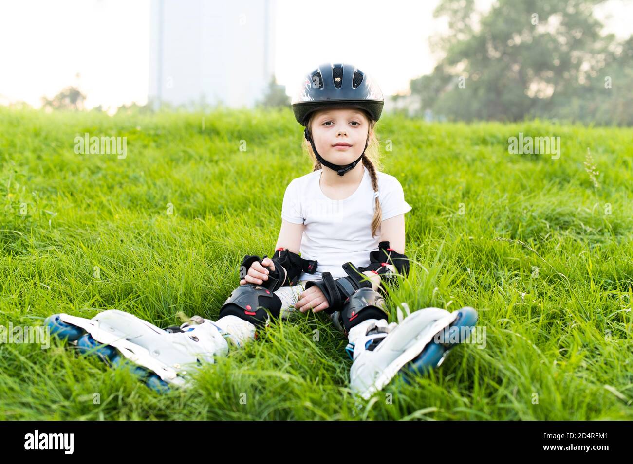 Niños con almohadillas de protección y casco de seguridad. Patinador joven en el parque Foto de stock