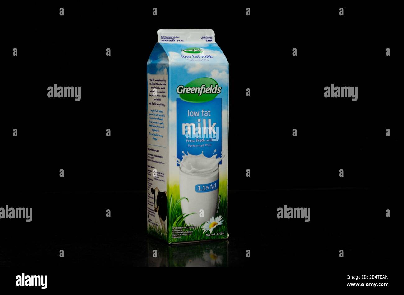 Vista derecha de un litro de una caja de leche baja en grasa de la Marca Greenfields originalmente de Malang, Indonesia, aislada en un fondo negro. Foto de stock