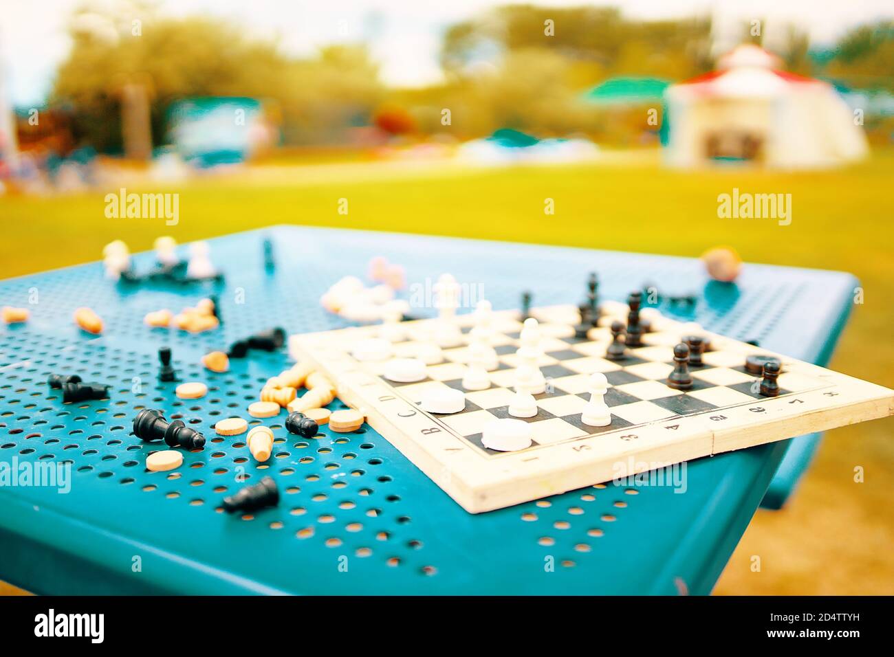 Ajedrez y damas están esparcidos en la mesa del parque. Un juego intelectual para desarrollar estrategias y tácticas. Pasatiempo útil en la calle. Entretenimiento en el complejo. Tablero de ajedrez y piezas en la mesa. Foto de stock