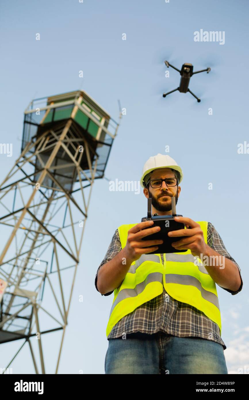 Un operario de aviones teledirigidos piloteando un avión junto a una torre Foto de stock