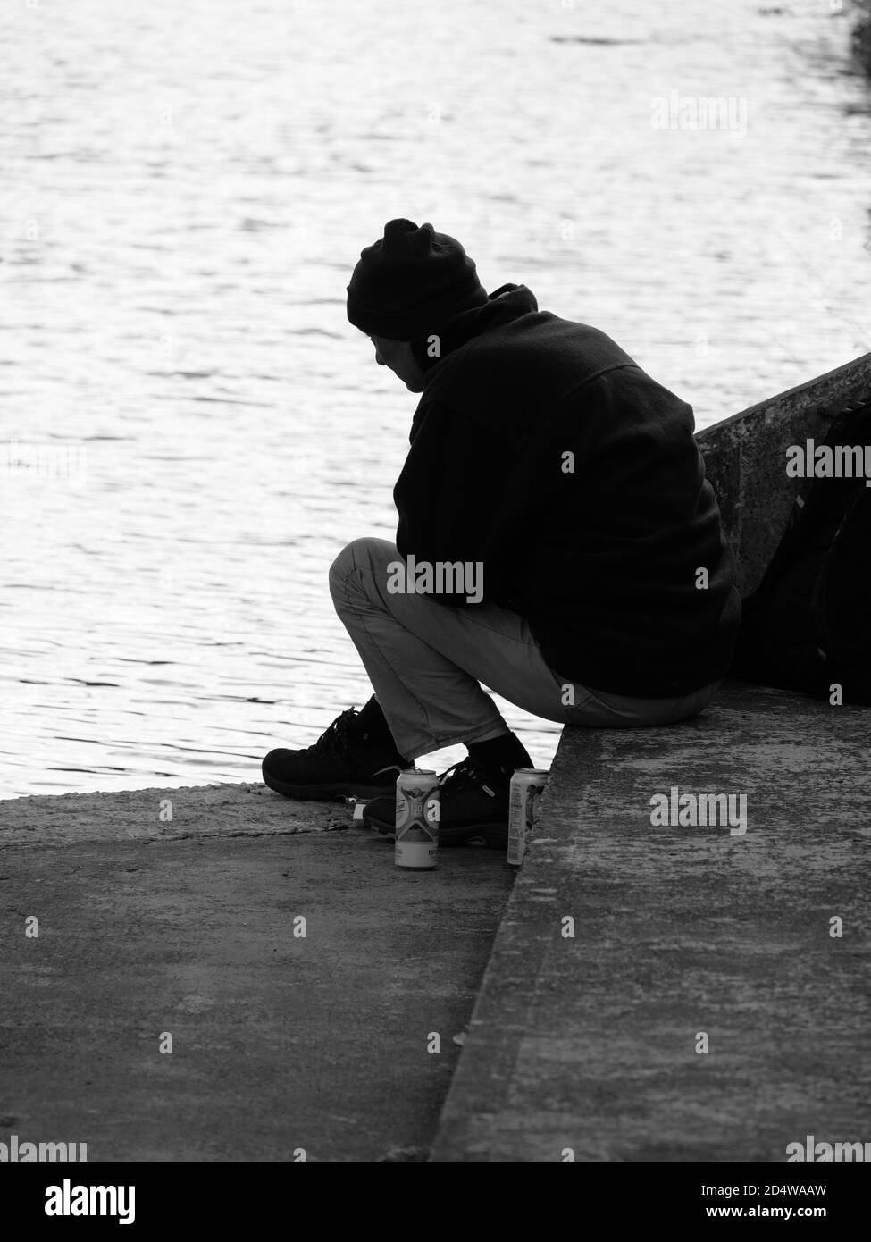 Un hombre solitario se sienta con su cerveza junto al agua Fotografía de  stock - Alamy