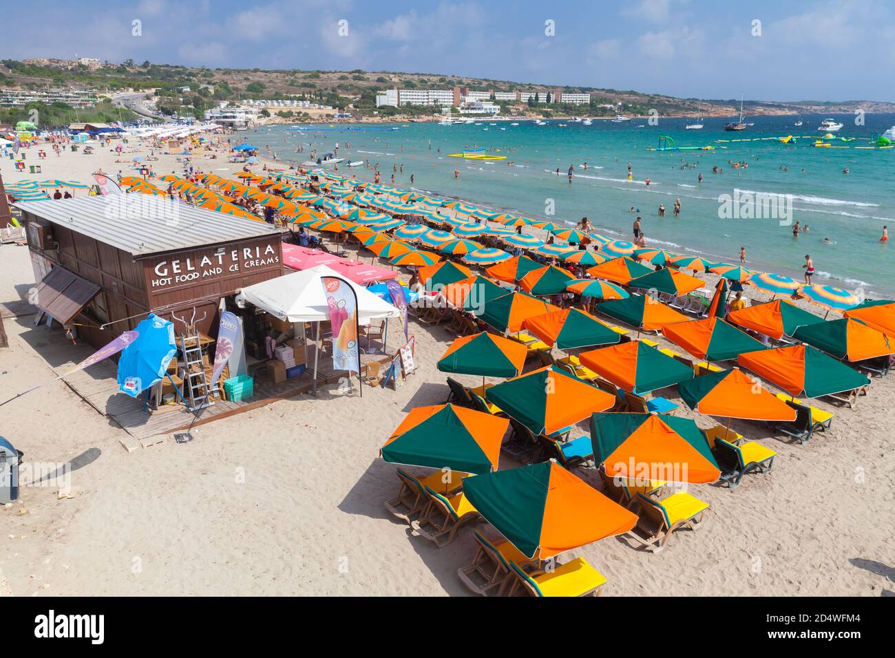 Mellieha, Malta - 30 de agosto de 2019: Popular playa pública con restaurantes y sombrillas, la gente descansa en la costa del mar Foto de stock