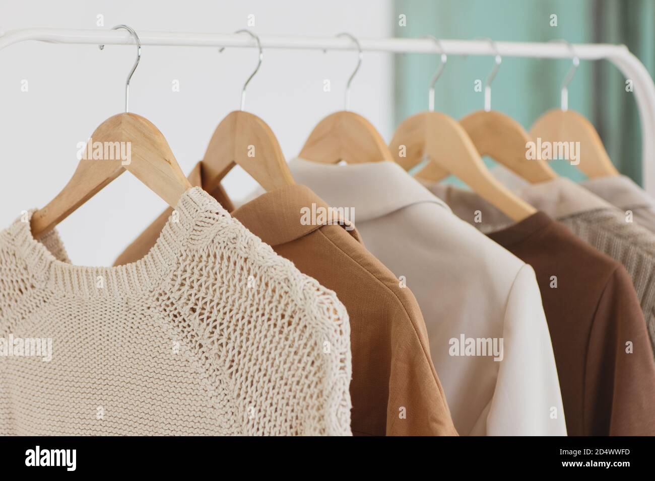 Ropa colgada en perchas de madera en la tienda de moda closeup. Foto de stock