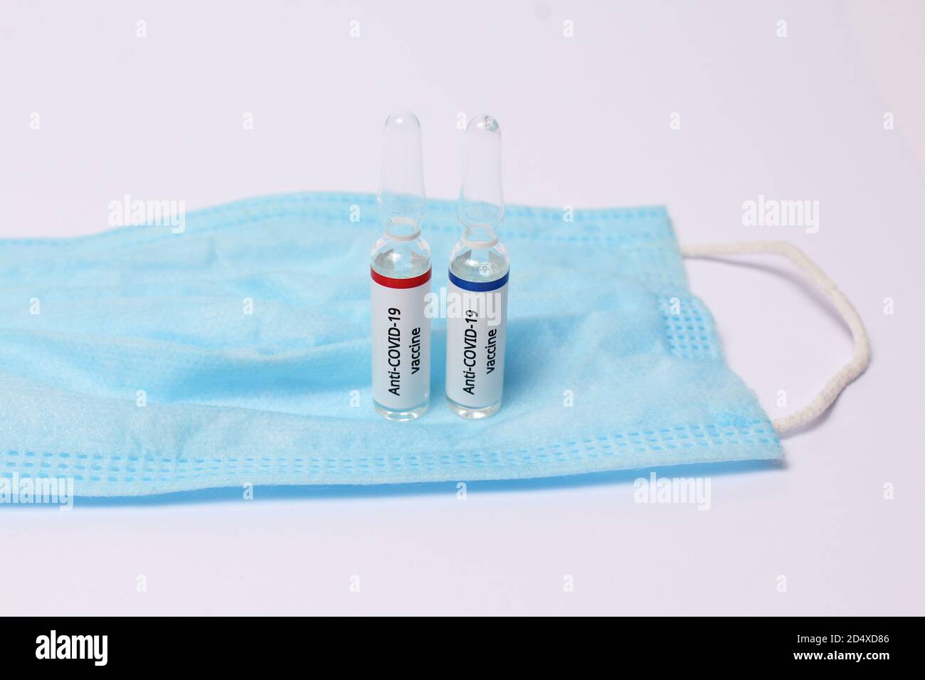 Dos ampollas de medicamento con vacuna anti covid-19 en máscara de protección sobre fondo blanco Foto de stock