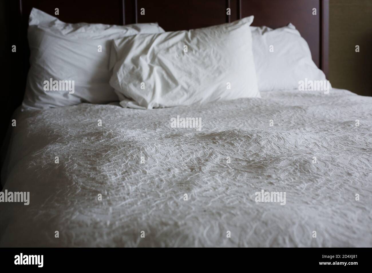 Una cama muy llena de bultos con colcha blanca y almohadas Fotografía de  stock - Alamy
