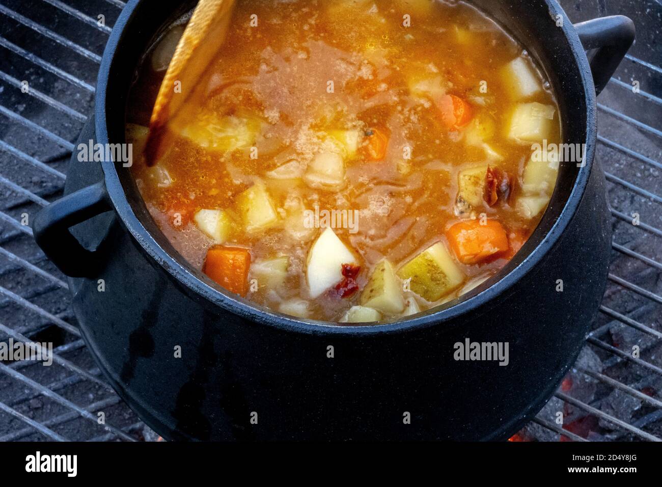 Estofado cocido al fuego al aire libre en una olla de hierro fundido una  parrilla Fotografía de stock - Alamy