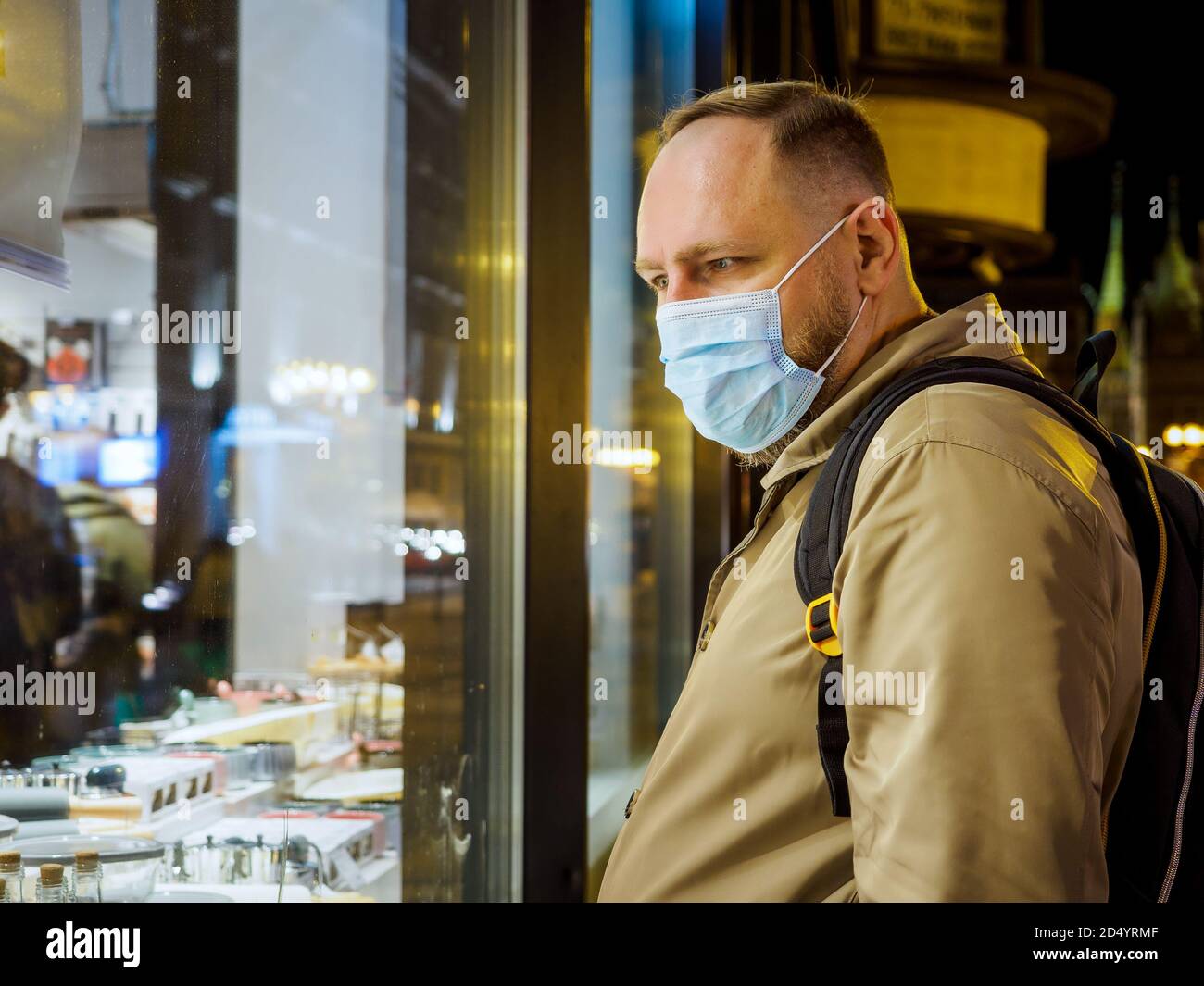 Hombre adulto con máscara caminando en una ciudad europea nocturna. La máscara es una cosa necesaria en la nueva realidad normal Foto de stock