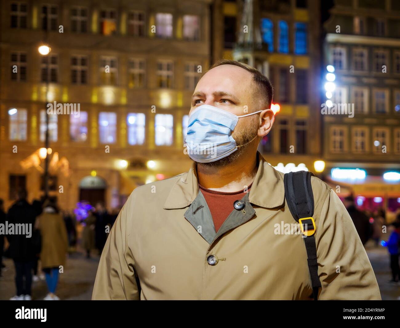 Hombre adulto con máscara caminando en una ciudad europea nocturna. La máscara es una cosa necesaria en la nueva realidad normal Foto de stock