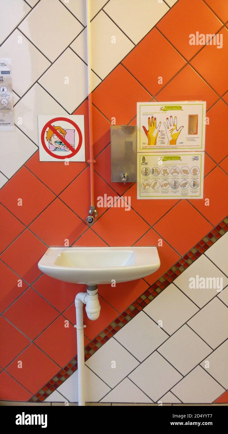 Pequeño lavabo con dispensador de jabón y normas de higiene, Francia Foto de stock