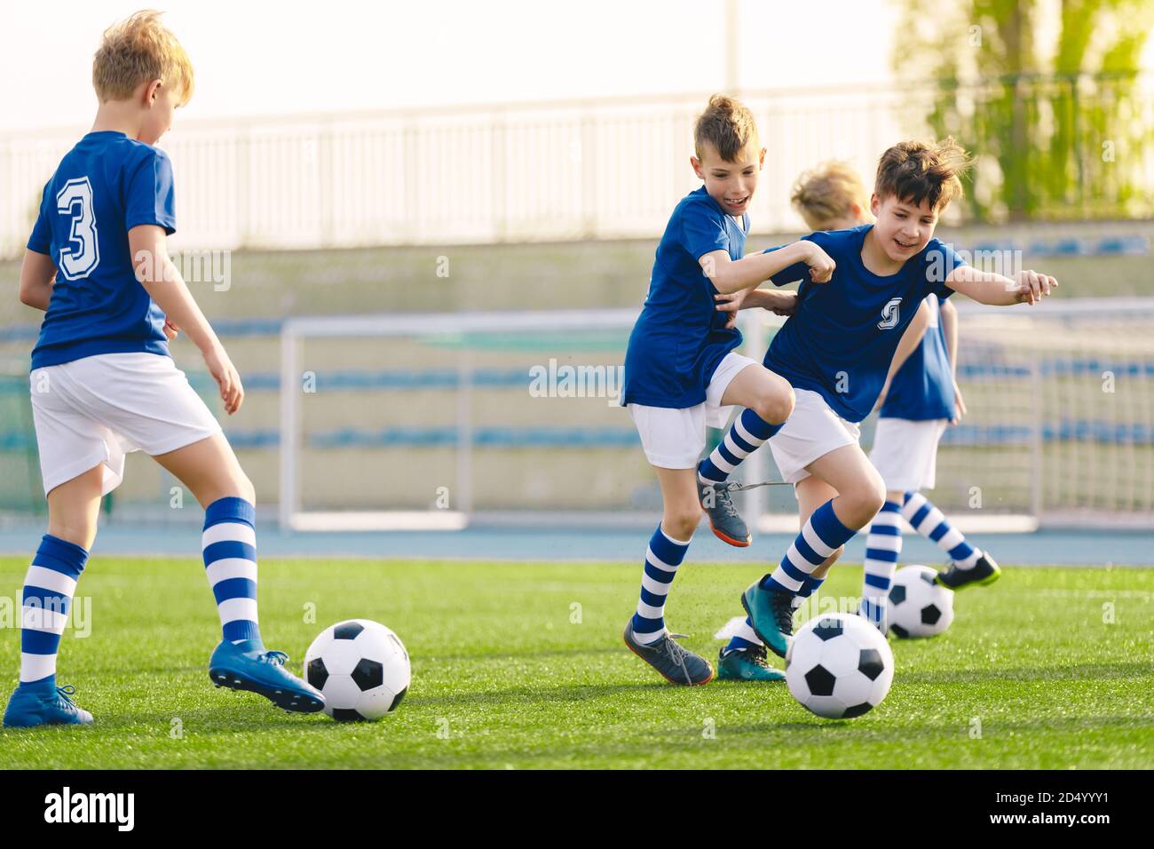 Niños jugando al juego de entrenamiento de fútbol. Niños felices pateando pelotas de fútbol en