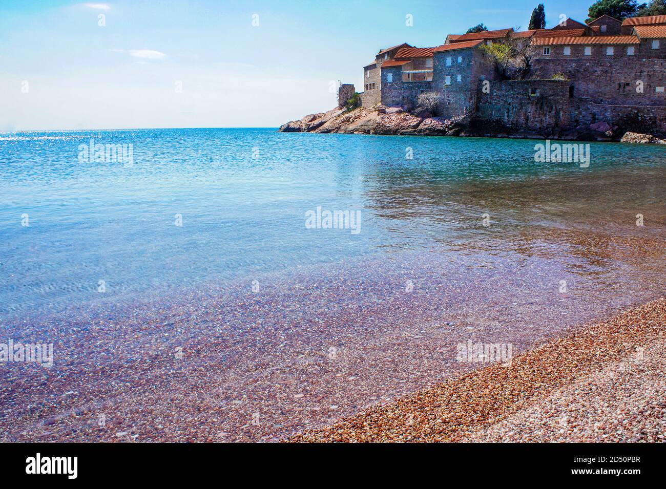 Mar Mediterráneo turquesa y costa con pequeñas guijarros de naranja. Isla de San Esteban Foto de stock